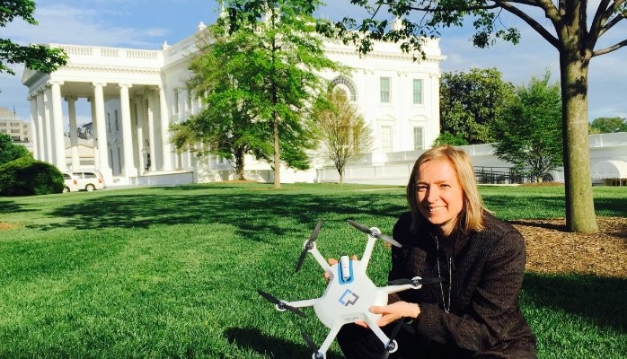 helen greiner posing in front of the white house holding a small robot