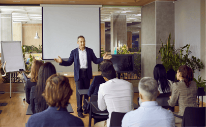 business man leading a meeting and speaking in front of group of listeners