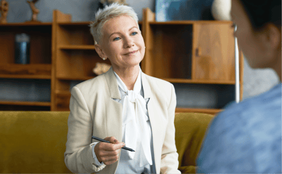 woman in business suit holding pen and looking at someone out of frame