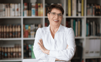 Woman with crossed arms smiling in front of bookcases 