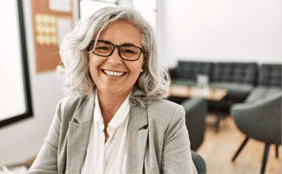 woman with glasses in gray blazer smiling in office