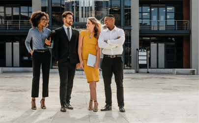 Four professionals smiling outside.