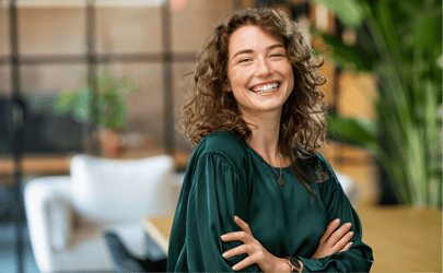 woman with curly hair smiling with arms crossed