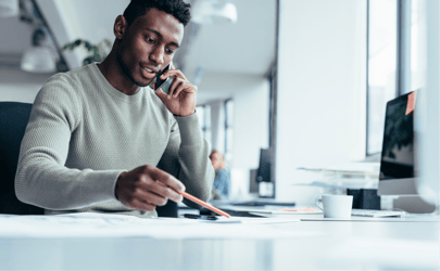 A professional chatting on the phone at their desk.