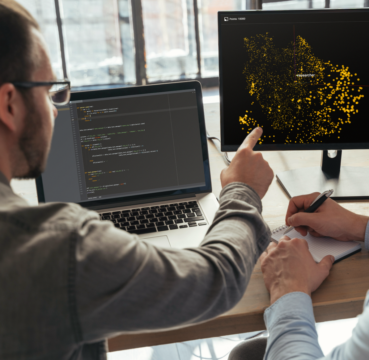 Man sitting at desk pointing at computer monitor with AI/ML graphics