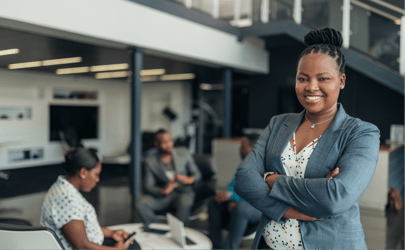 woman standing and smiling in front of group of office workers 