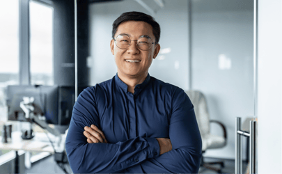 Man with glasses and in blue shirt smiling with arms crossed