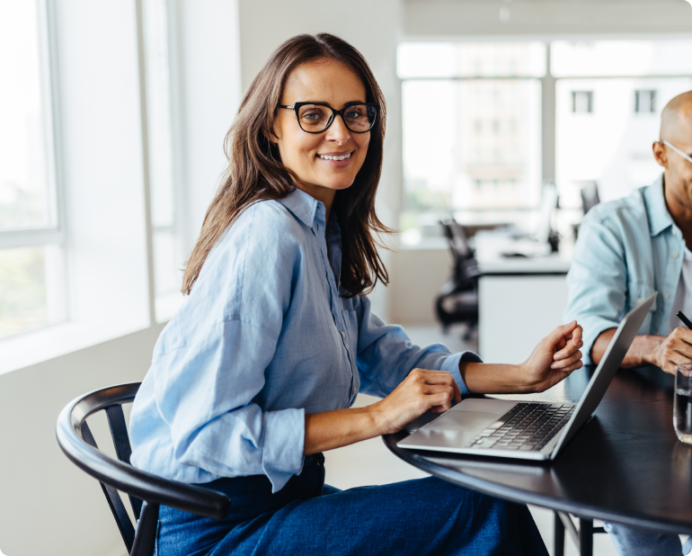 business woman sitting at desk smiling with open laptop