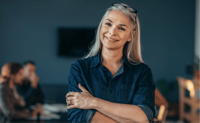 Woman smiling in a meeting room with arms crossed