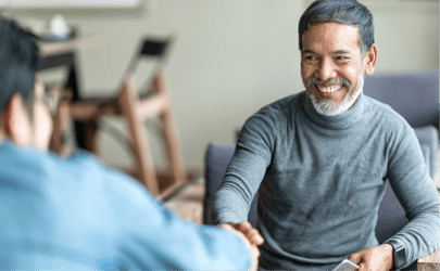 man sitting across woman off camera and shaking her hand while smiling