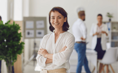 woman standing and smiling in front of two other people and board with notes