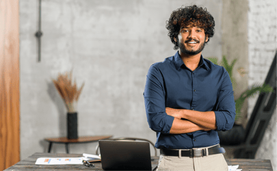 Business man leaning against desk and smiling with crossed arms