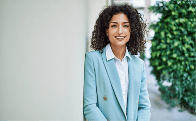 business woman in blue suit smiling and leaning against wall