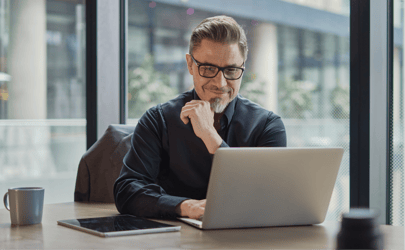 man sitting in front of laptop with hand on chin