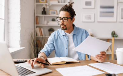 Recruiter searching resumes on laptop and holding papers