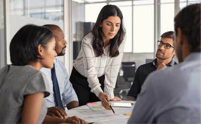 Executive at a meeting table pointing to documents