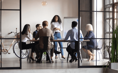 woman leading a business meeting and talking to a group of five other people