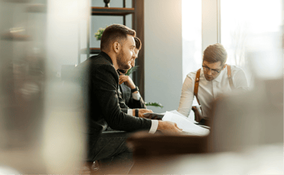 three business men in a room reviewing a document