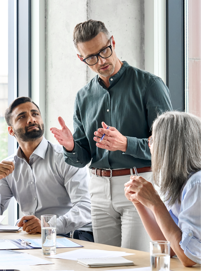 man standing with hands out in front of him explaining something to two other colleagues