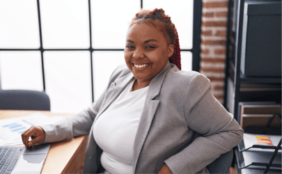 woman in gray blazer sitting in office and smiling