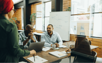 group of diverse office workers meeting around documents with whiteboard in background