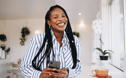 woman in striped blouse smiling and holding cellphone