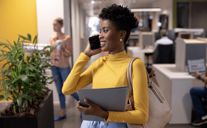 woman holding and talking on the phone and holding a folder with her other arm