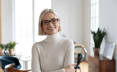 woman in white turtleneck and glasses smiling at camera