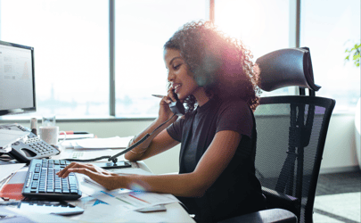 woman on the phone and using other hand to type on keyboard