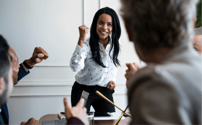 woman leading a board meeting and fist pumping in celebration