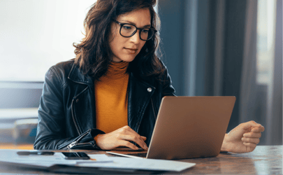 woman with glasses working on her laptop