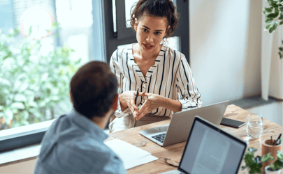 woman professional speaking to colleague at a desk