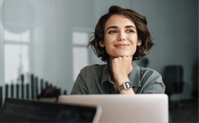woman sitting at desk, resting her chin on her hand and smiling