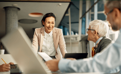 woman leaning over desk smiling and leading a meeting with man looking at her