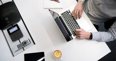 hands typing on laptop with cup of coffee on desk