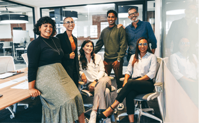 group of 6 engineering professionals sitting and standing in an office smiling at camera