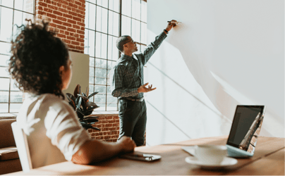 man leading meeting and pointing at whiteboard