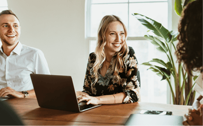 woman smiling and typing up an email on laptop