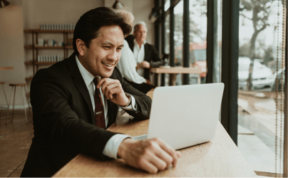 man with hand on chin looking and smiling at laptop