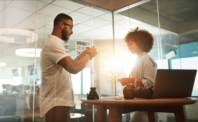 man and woman talking in office with sunlight shining between them