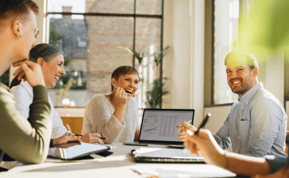 group of professionals smiling and working around a laptop together