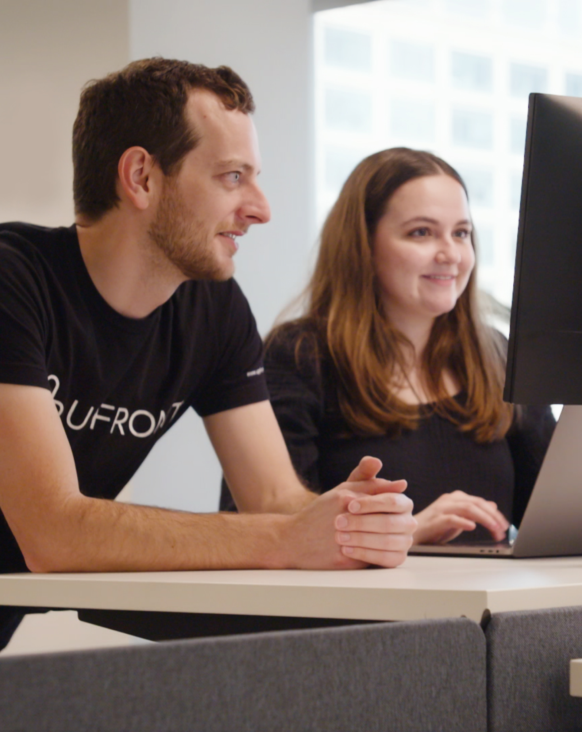 two upfront healthcare employees working on computer together and smiling