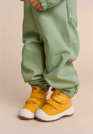 child's legs modeling a pair of reima brand outdoor pants and yellow shoes