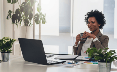 business woman drinking coffee and smiling at laptop