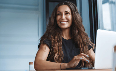 woman with long brown hair smiling near laptop