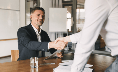 man shaking someone hand over a desk