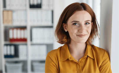 Woman with short hair smiling in front of office shelves