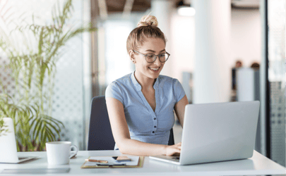 woman with glasses sitting and working on laptop