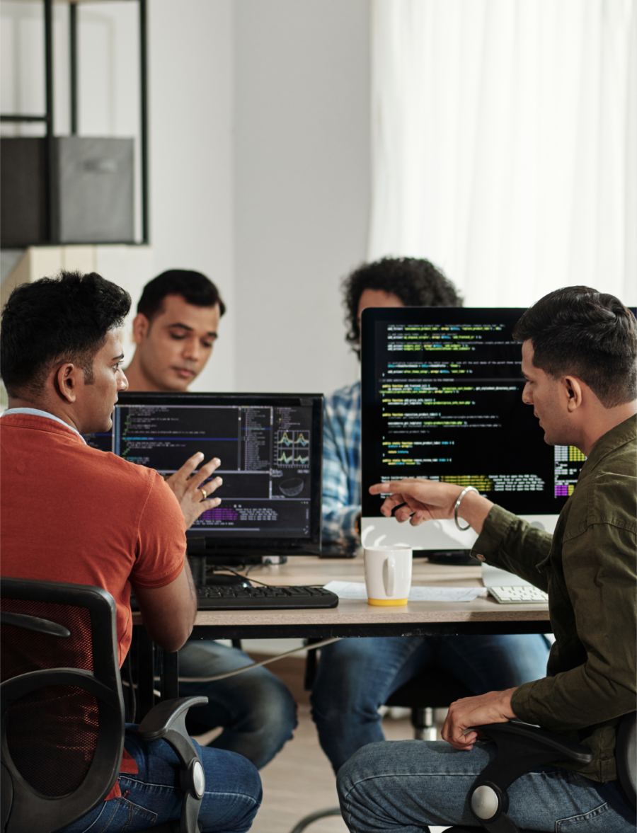 four engineers/tech professionals working together on computer screens with lines of code