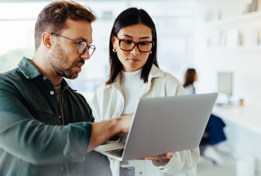 man and woman with glasses reviewing something on laptop screen together